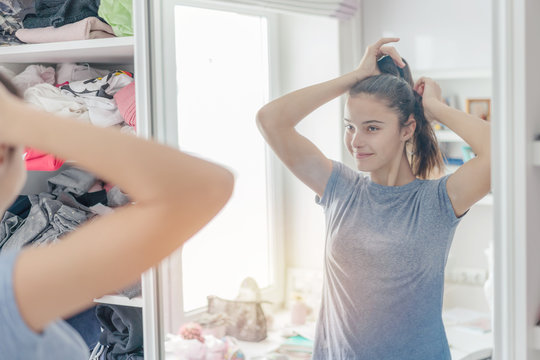 Girl Makes Hairstyle Standing In Front Of The Mirror In The Room