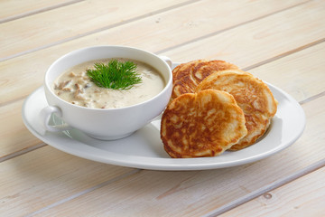 Fritters with mushroom sauce. Traditional Slavic pancakes with fat mushroom and flour sauce.
