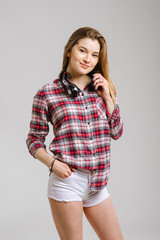 Happy young caucasian woman wearing shirt and shorts with headphones smiling and posing on the grey background