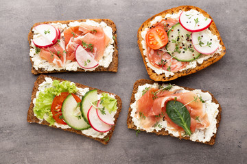 Sandwich with cereals bread and salami on dark marble background.