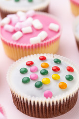 Colorful cupcakes on a pink background.