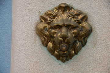Door bell with a lion's head, antiqued burnished brass button. Electrified doorbell button of a house in Burano, Venice.