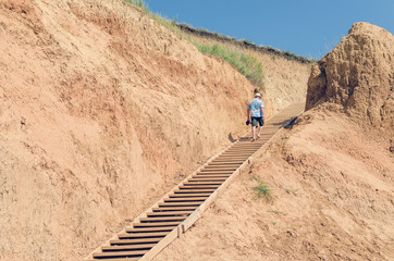 Obraz premium Young man in a hat rises up the wooden stairs