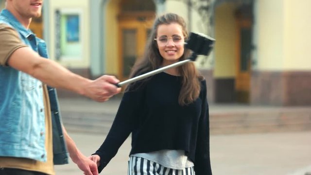 Young couple happy taking selfie photo with smartphone. Young stylish couple making picture with selfie stick in the city.