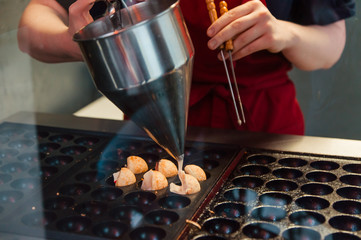 adding the batter to takoyaki in the street food cafe 
