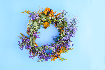Wreath of wild flowers on soft blue paper background.