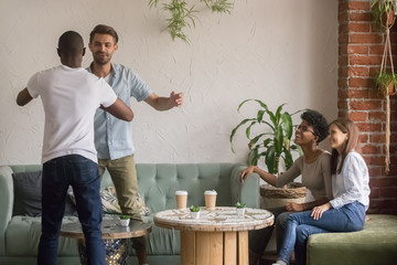Happy diverse male friends greeting at reunion meeting in cafe