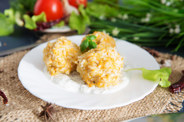 Meatballs with chicken and rice in sour cream sauce. Wooden background.