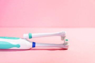 Two electrical toothbrushes on a soft light pink background