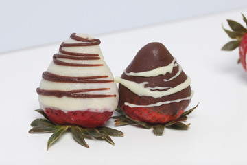 Strawberries glazed in black and white chocolate. Lie on a white background.