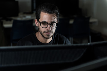 View over a screen of the face of a young computer science student working with the computer.