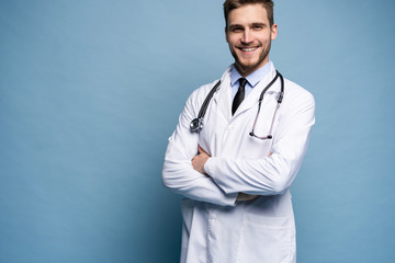 Portrait of confident young medical doctor on blue background.