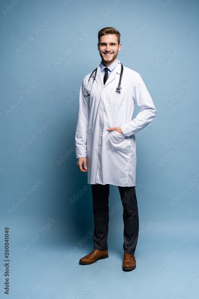 Wall mural Full length young medical doctor on blue background.