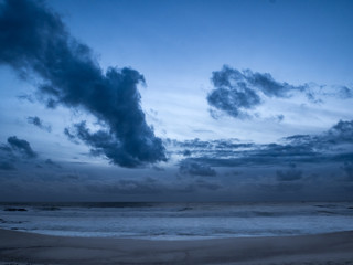 Dark moody clouds over ocean at dusk on beach
