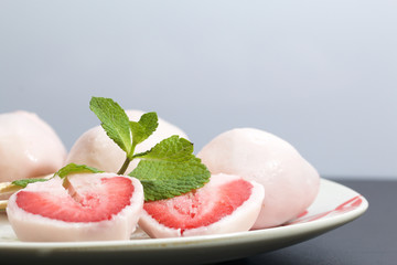 Strawberries in yogurt. Berries are dressed on wooden skewers and dipped in yogurt. Nearby are two halves of dessert. Visible red juicy strawberry flesh. Decorated with mint leaves.