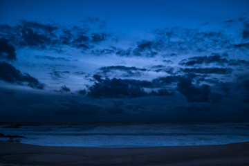 Dark moody clouds over ocean at dusk on beach