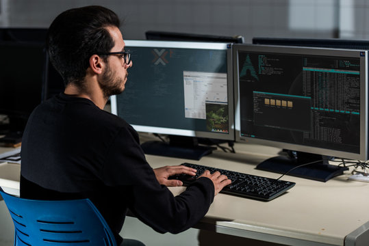 Young computer science student developing with his computer on a Linux System over double screen system