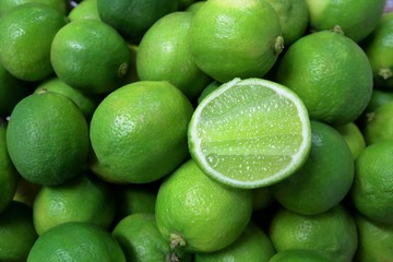 Slice lime on pile of fresh green limes fruit.