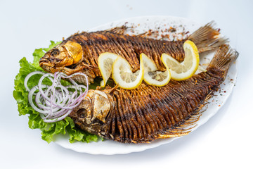 Grilled carp fish on the white plate over white