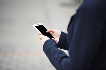 The business lady uses a smartphone on the street