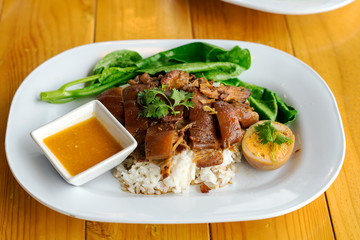 Stewed pork leg on rice with boiled egg on wood table