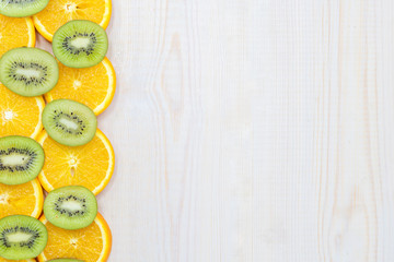 Fresh kiwi and orange on wooden background. Empty space for text