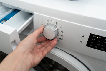 Close-up. Female chooses the eco mode in an automatic washing machine. Side view