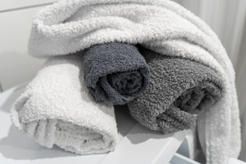 Clean rolled cotton towels of gray shades on the washing machine in the bathroom. Top-side view