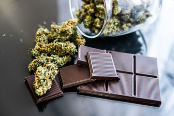 Chocolate with cannabis and buds of marijuana on the table. Concept of chocolate with cannabis herb...