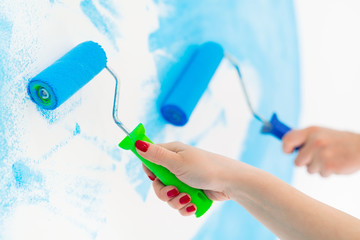 blue color painting wall with roller in hand.