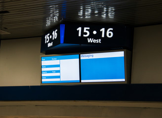 Sign on a wall near the ceiling Top part shows track numbers and the two screens below is a template for train information