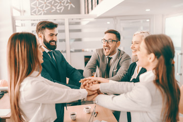 Group of cheerful corporate businesspeople in formal wear stacking hands at meeting in boardroom. Catch your people doing something right and let them know you appreciate it. - obrazy, fototapety, plakaty