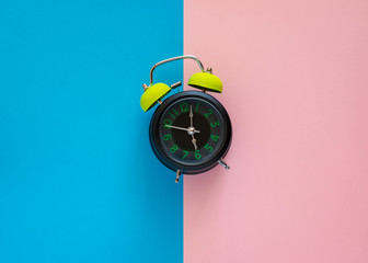Alarm clock on two tone pink and blue paper. - 260050414