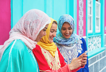 Happy muslim women watching on mobile smart phone in the college - Arabian young girls having fun...