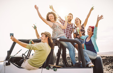 Happy friends taking selfie with mobile smart phone on convertible car - Millennial young people having fun making party during their road trip - Vacation, tech and youth holidays lifestyle concept © Alessandro Biascioli