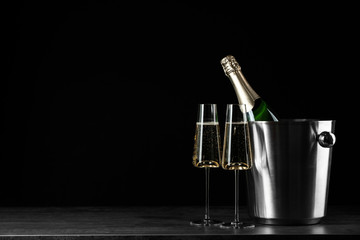Glasses of champagne near bucket with bottle on black background, space for text © New Africa