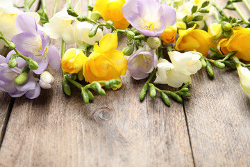 Fototapeta premium Beautiful fresh freesia flowers on wooden background, closeup. Space for text