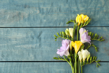 Beautiful fresh freesia flowers on wooden background, top view. Space for text