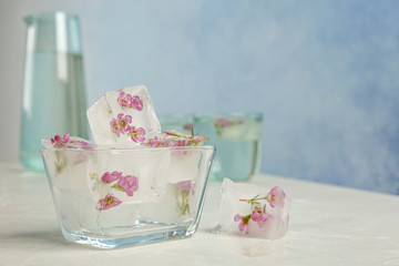 Bowl with floral ice cubes on table. Space for text