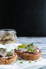 smorrebrod open sandwich with rye  bread herring boiling egg chopped green onions on craft paper on rustic wooden table close up vertical orientation