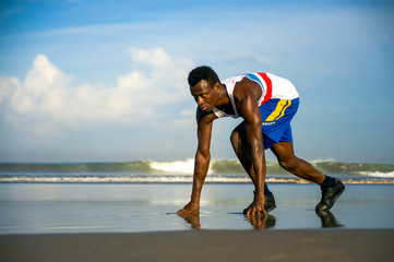 young athletic and attractive black African American runner man doing running workout training on desert beach in fitness and wellness isolated on blue sky