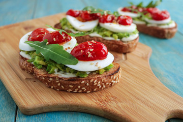 mashed avocado on toast bread with boiling egg cherry tomatoes cream cheese healthy sandwich soft focus