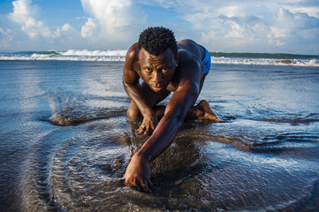 young attractive and sexy black afro American man with athletic muscular body posing cool in sea water on desert beach in male beauty and plasticity concept