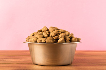Bowl with dog food on a wooden table. Close up.