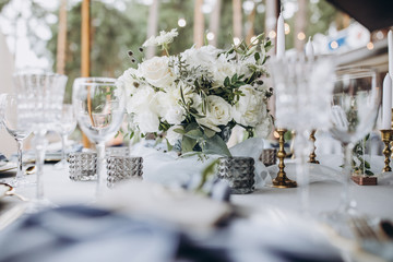 banquet table is decorated with plates, cutlery, glasses, candles and flower arrangements