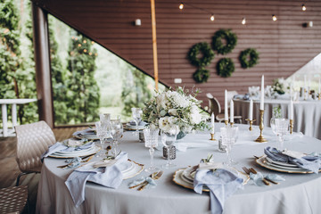 banquet table is decorated with plates, cutlery, glasses, candles and flower arrangements