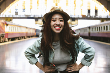 Portrait of young Asian backpacker female standing at train station. Travel lifestyle concept.