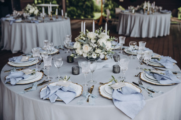 banquet table is decorated with plates, cutlery, glasses, candles and flower arrangements