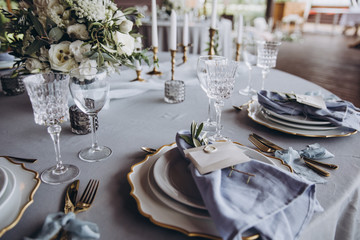 banquet table is decorated with plates, cutlery, glasses, candles and flower arrangements