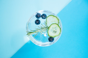 A glass of a gin and tonic drink with blueberries, cucumber and a rosemary twig isolated on...